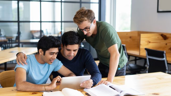 Focused students browsing on tablet computer and talking