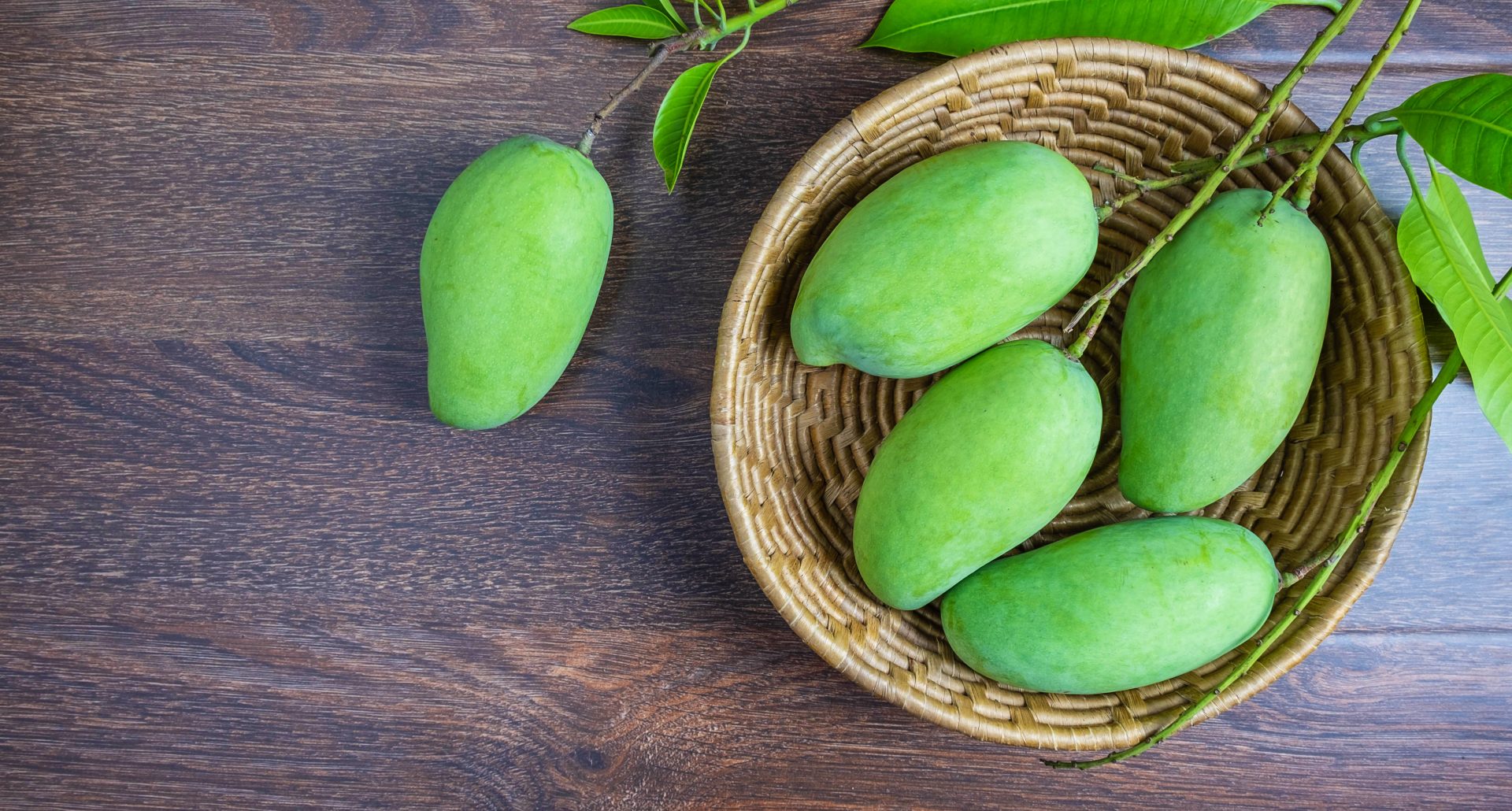 Fresh green mango fruit in a wooden basket